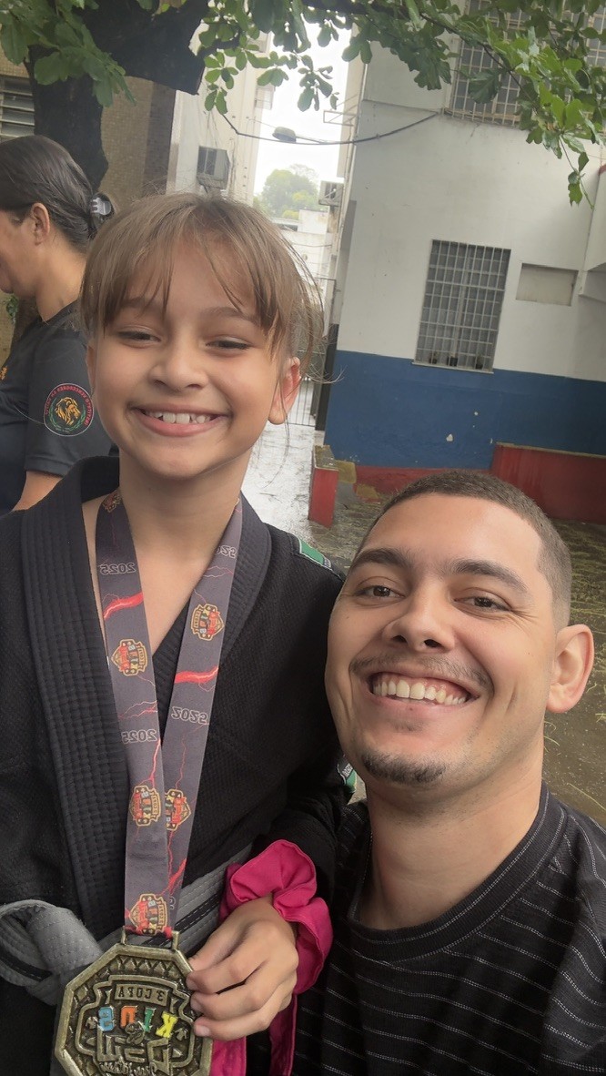 Thiago Antunes e uma criança com medalha sorrindo em uma competição de jiu-jitsu