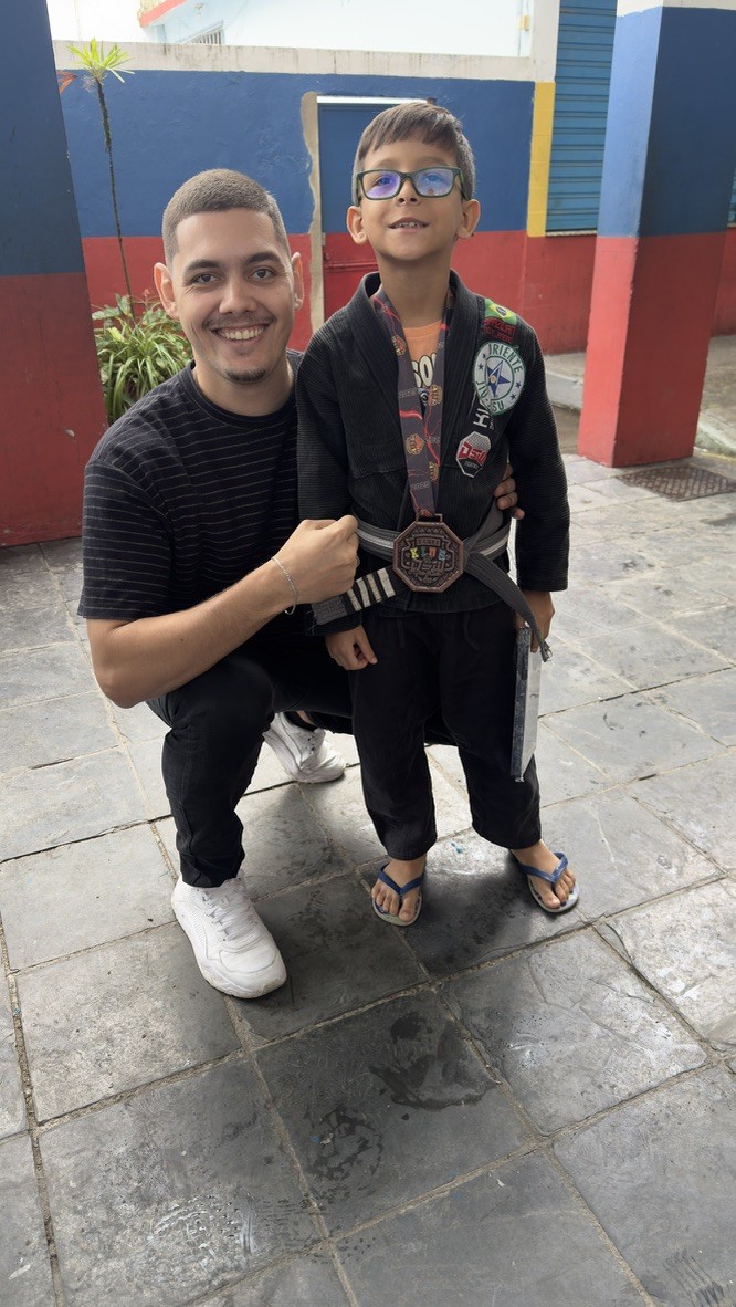 Thiago Antunes ao lado de uma criança com uma medalha de jiu-jitsu