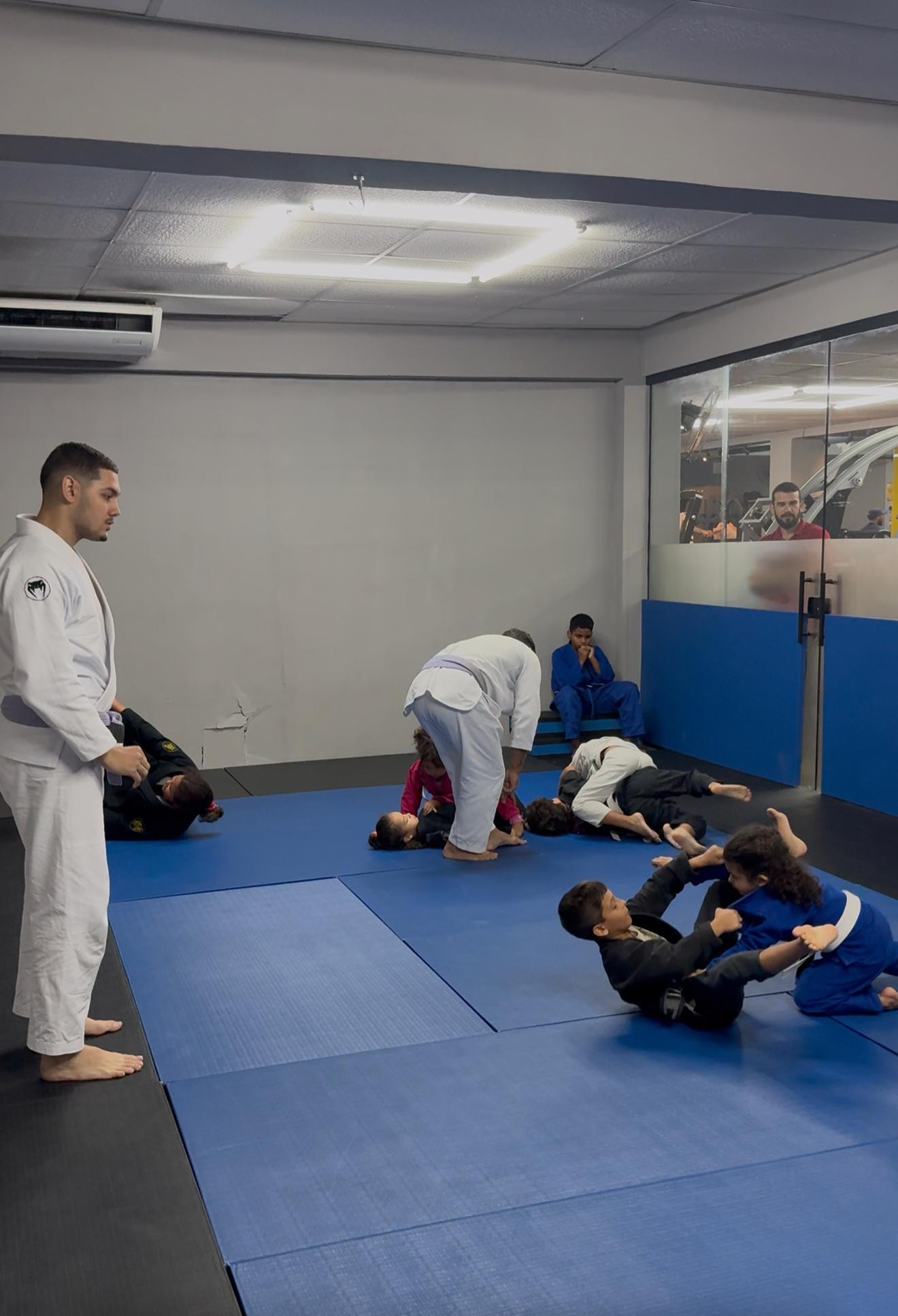 Thiago Antunes observando crianças praticando jiu-jitsu em duplas